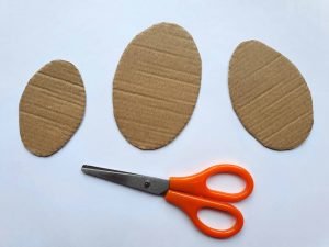 3 Cut-out cardboard eggs, with scissors next to them