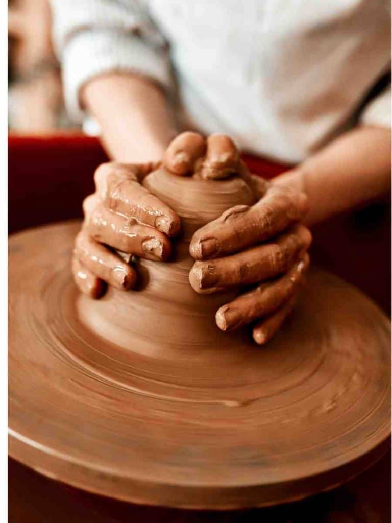 hands working clay on a pottery wheel