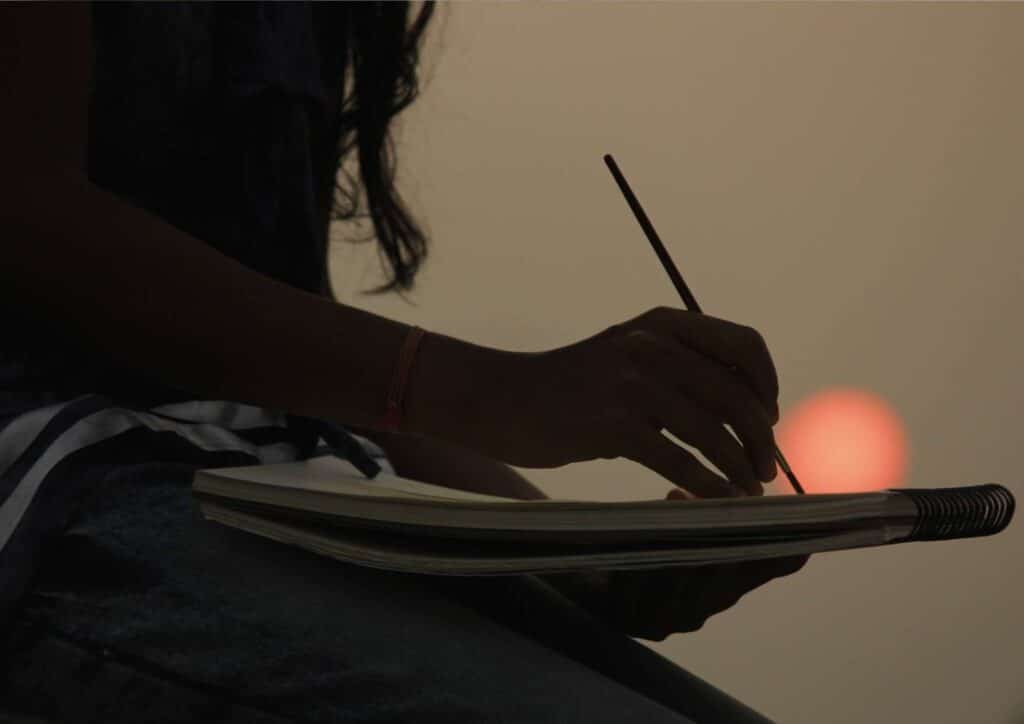 a woman drawing against a sunset